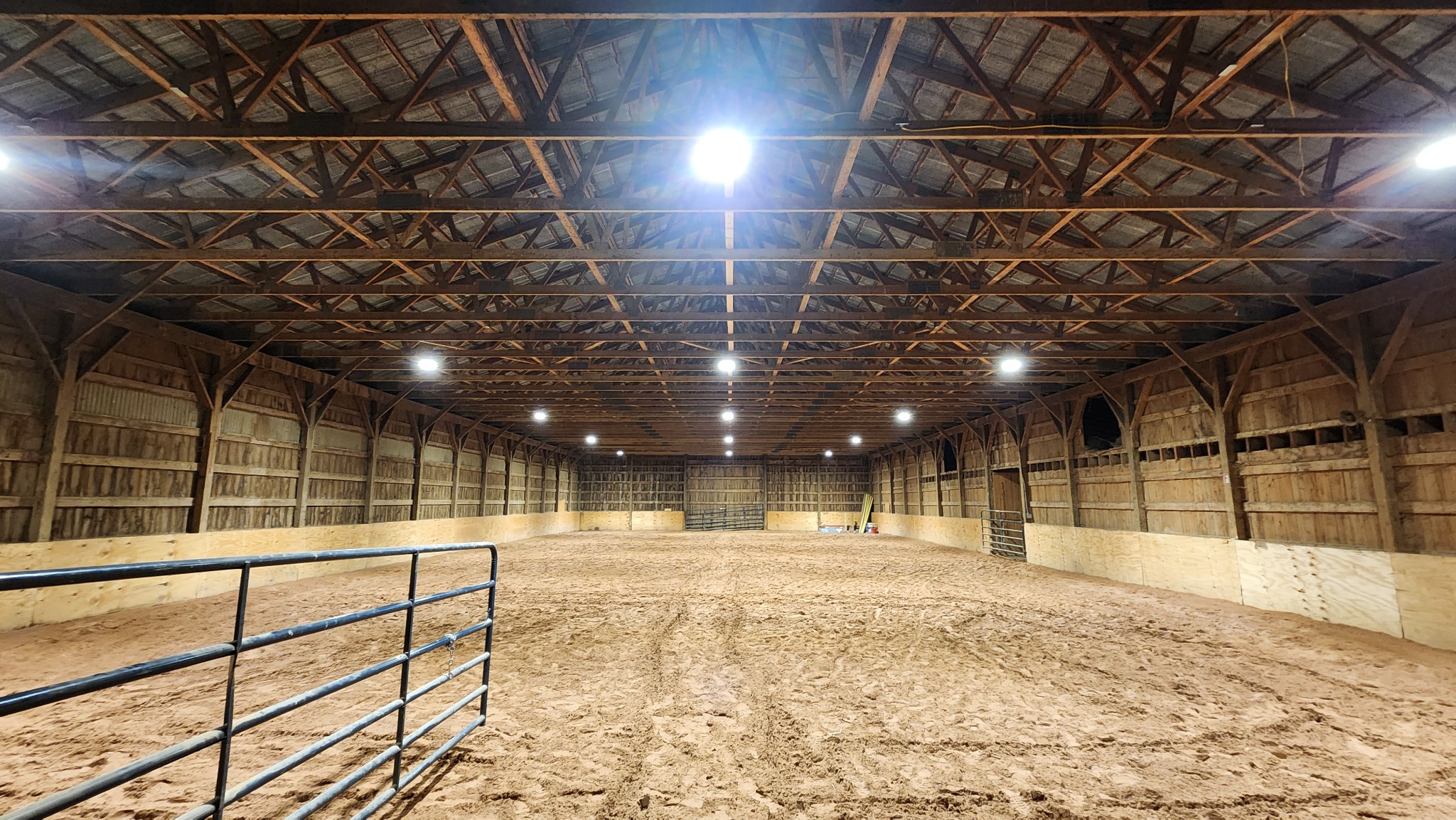 Overhead lighting installed throughout an indoor horse arena