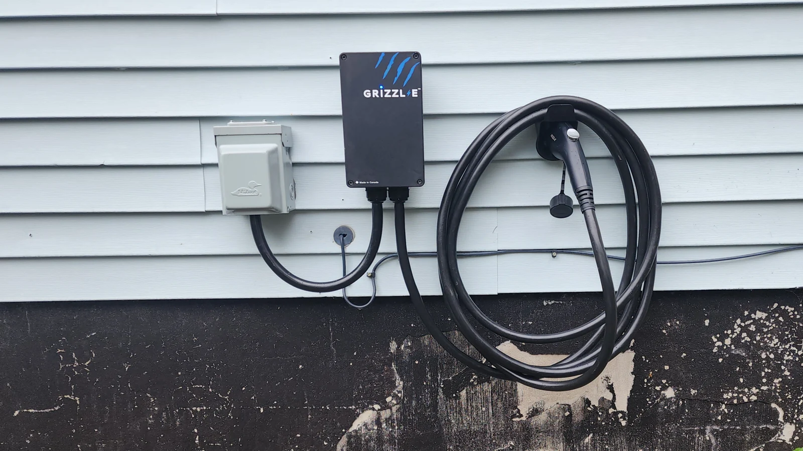 Outdoor EV charger installed on home siding with conduit