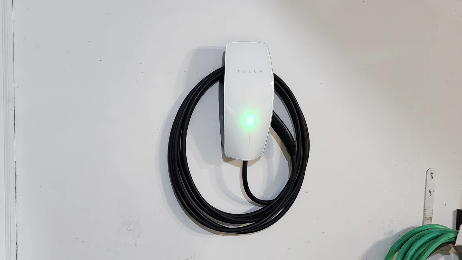 Tesla Wall Connector with cable arranged on a garage wall